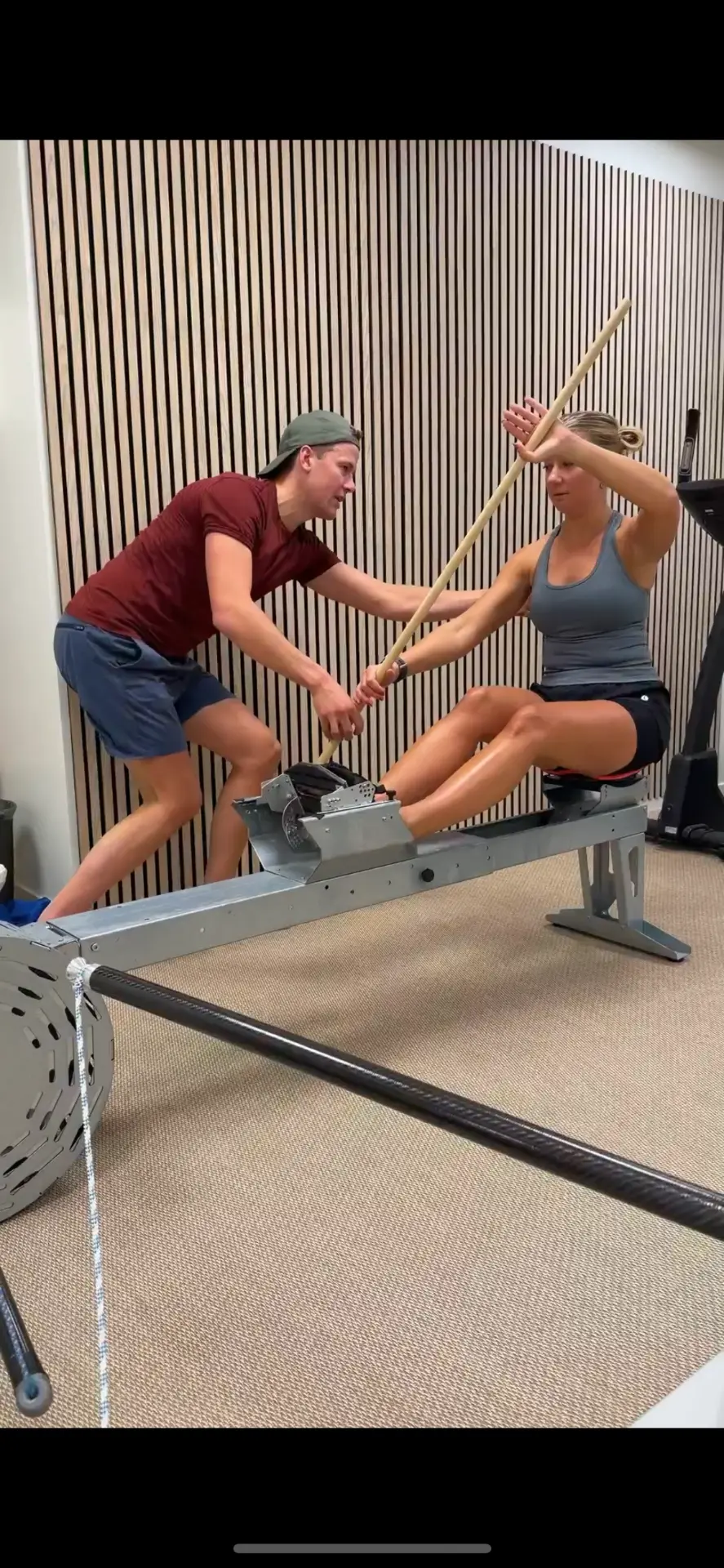 Joakim Lindberg coaching an athlete's paddle stroke on a kayak ergometer